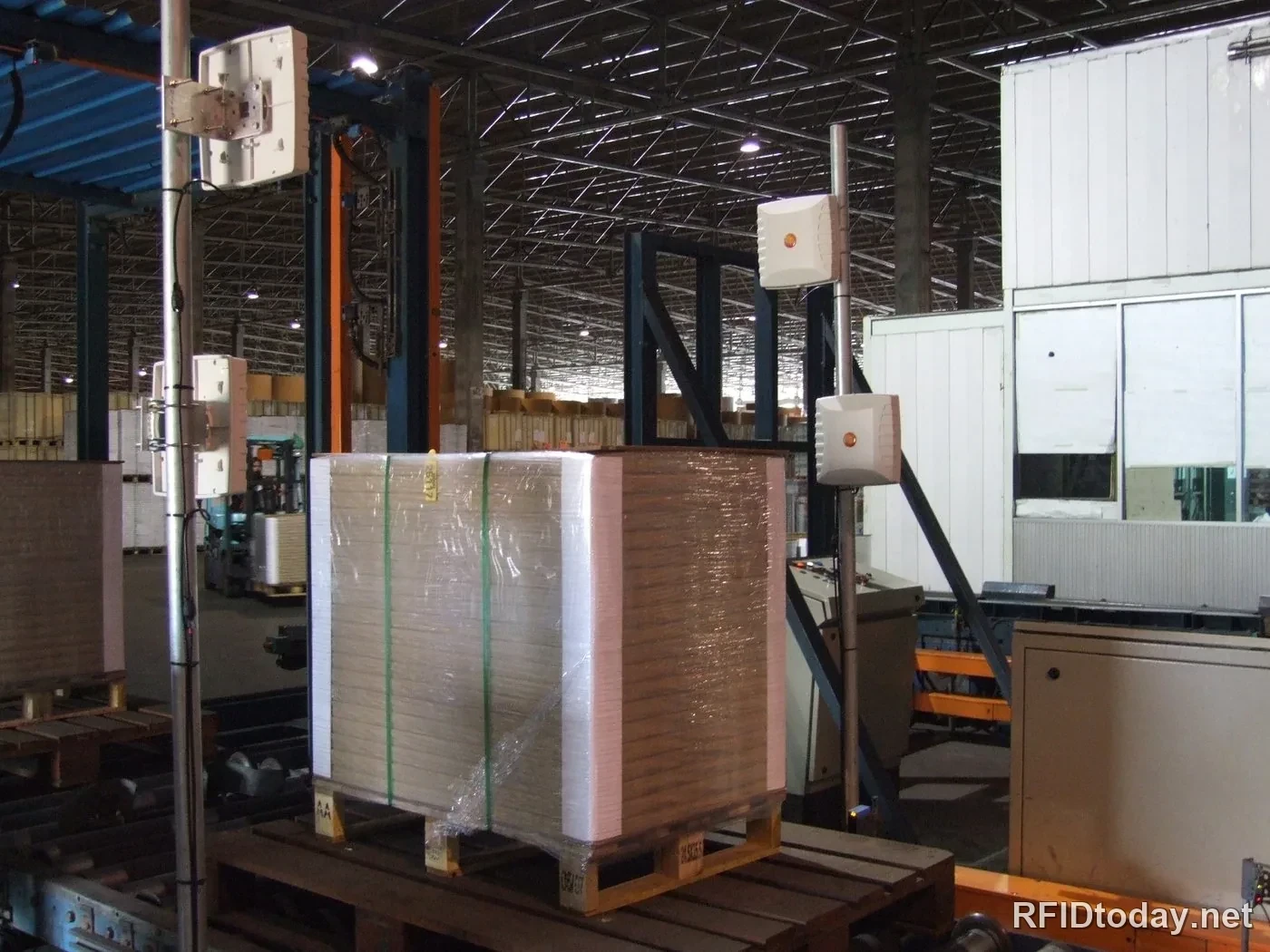 เสาอากาศ RFID สี่ตัวบนเสาสองข้าง กำลังอ่านพาเลทกระดาษที่เคลื่อนผ่านในโรงงาน