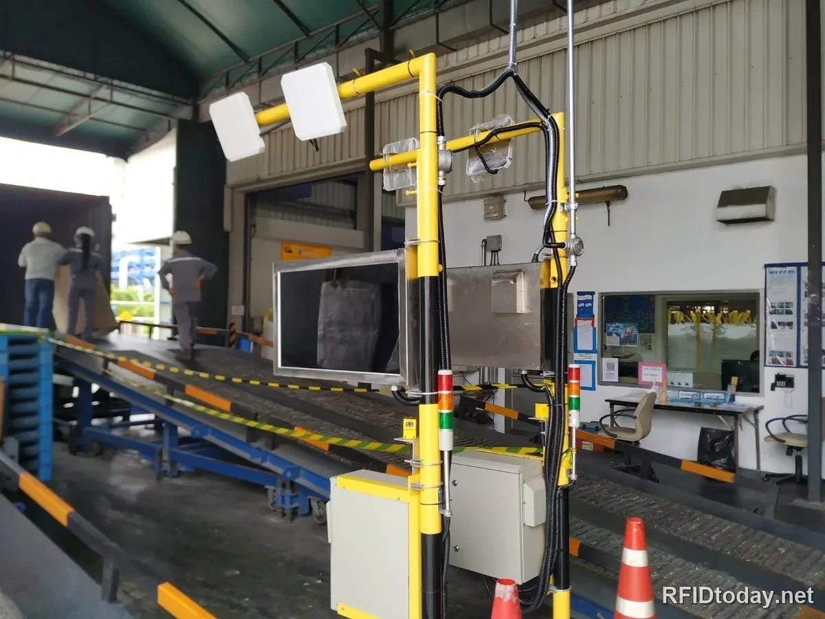 เสาอากาศ RFID สองตัวบนโครงเหลืองเหนือสายพานลำเลียง ที่จุดโหลดสินค้าขึ้นตู้
